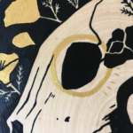 A painting on a wood slice featuring a bear skull against a black background with golden poppies entangled around the skull.