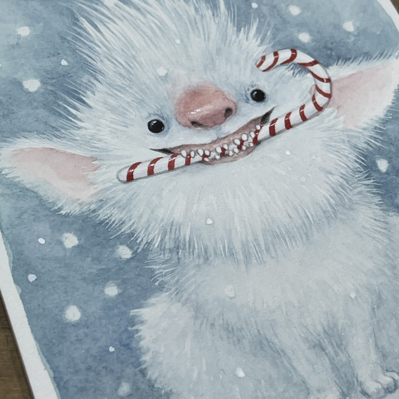Cute furry white creature with candy cane in mouth