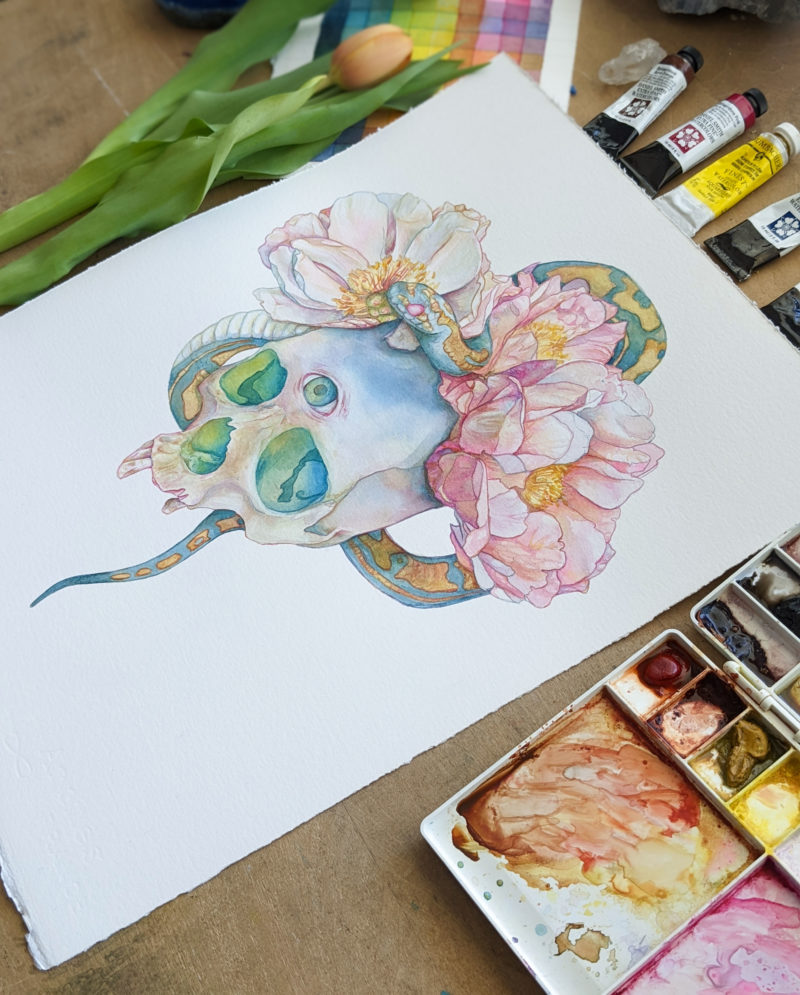 a watercolor painting of a skull with a crown of peonies and a snake entwined in the flowers. The eyes of the skull glow green.