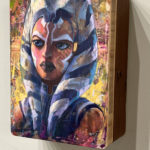 A painting of Ashoka Tano by Rick Price on the wall.