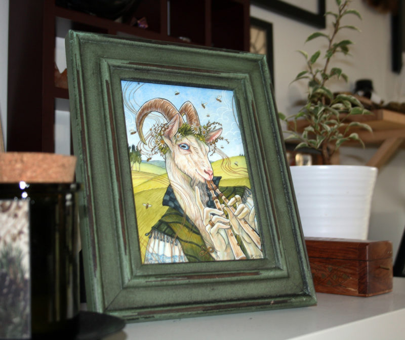Framed goat painting sitting on a bookshelf