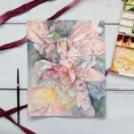 Pictured is a watercolor painting of a close up of peony flowers. The flowers are messy and complicated but still beautiful and painted in cool pink tones for the brighter areas and fading into deep blue-greys for the darker areas. In the center of the painting there is an image of a skull overlayed on the flowers as if a ghostly pink skull was a part of this lush beauty.