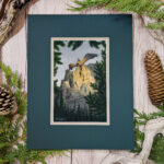 Golden Hour dragon standing on a cliff with wings out above a forest painted in watercolor photo of artwork in mat