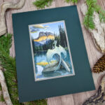 A pale greenish blue dragon perches on a tree in a lake, facing the mountain range as the sun sets across it