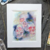 Pictured is a watercolor painting of three overlapping skulls floating amidst rich watercolor washes.