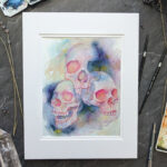 Pictured is a watercolor painting of three overlapping skulls floating amidst rich watercolor washes.