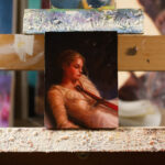 A miniature oil painting of a girl lying down, looking at the sword resting over her chest and stomach.