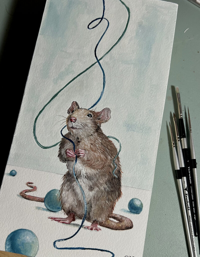 Painting of playful rat holding blue string with teal beads around the floor. Artist paintbrushes to the right of the work.
