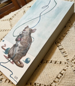 Side view image of painting of playful rat holding blue string with teal beads around the floor