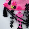 A shiny black dragonfly rests on a bright pink vintage fan decorated with a lot of fringe, beads and cascading flowers