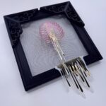 Pink iridescent ribcage holding white heart with gold veins, dripping gold blood