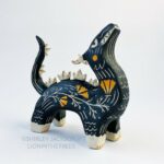 Sgraffito dragon totem done with black and orange underglazes, and finished with gold overglaze in some areas. The dragon has it's head reared up and California Poppies have been carved into it's side along with other markings. This photo shows the right side of the sculpture.