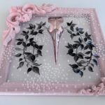 Detail of pink metallic filigreed crow skull surrounded by black leaves