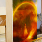 A side view of an oil painting containing a young girl standing by a raging fire, and sparkling arch of a rainbow overhead