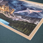 Flat scan view of a white dragon flying over a lake similar to Moraine Lake in Banff, Canada. A dark storm rises from behind the mountains, lit in a blazed line across the center from the setting sun. This photo is a close up of the corner of the painting where the signature is.