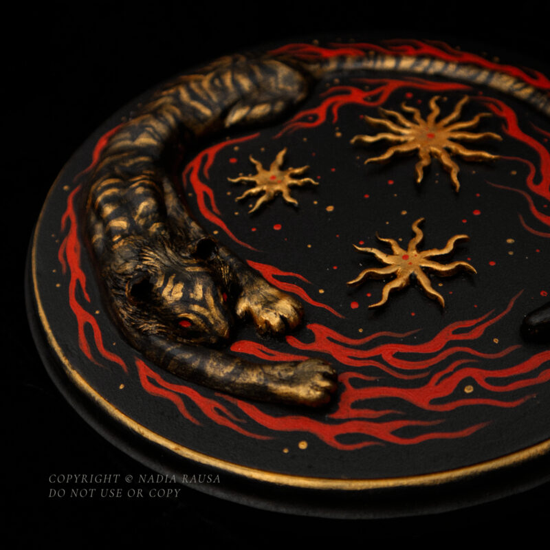 A relief sculpture of a tiger surrounded by flames and stars on a round wooden board against a dark background.