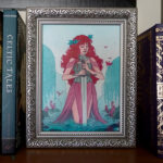 A framed mixed media painting of a long haired woman with a sword, in water, surrounded by lily pads, birds, and willow trees. The framed painting is displayed on a bookshelf.