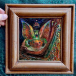 A brightly colored painting of a bat framed for display
