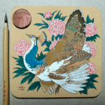 Painting on a square coaster of a pied peahen surrounded by pink peonies, photographed with a penny and a traditional Chinese brush for scale.