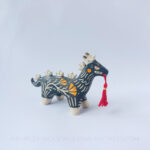 Sgraffito ceramic dragon sculpture done with black and orange underglazes. The piece features my signature California Poppies motif, gold luster details, and a red tassel hanging from the dragon's mouth.