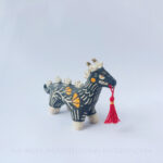 Sgraffito ceramic dragon sculpture done with black and orange underglazes. The piece features my signature California Poppies motif, gold luster details, and a red tassel hanging from the dragon's mouth.