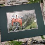 Photo of artwork of a rusty red dragon perched on a twisted dead tree looking out at a misty mountain range.