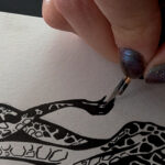 Close up of a hand inking the tail of a giraffe