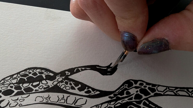 Close up of a hand inking the tail of a giraffe