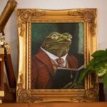 Whimsical frog portrait painting Professor Percival Croakley by Connie Resch, shown displayed on a bookshelf with books and decorative objects, perfect art for study, library, or desk decor.