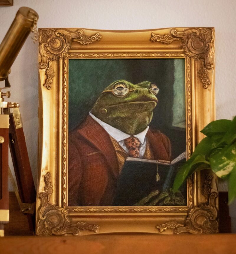 Whimsical frog portrait painting Professor Percival Croakley by Connie Resch, shown displayed on a bookshelf with books and decorative objects, perfect art for study, library, or desk decor.