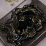 A photo of a sculpture of an eye surrounded by petals, branches, and leaves.