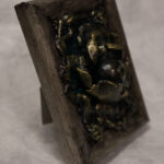 A photo of a sculpture of an eye surrounded by petals, branches, and leaves.