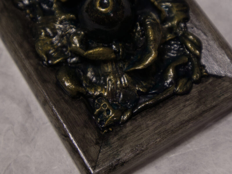 A photo of a sculpture of an eye surrounded by petals, branches, and leaves.