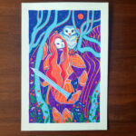 An artwork named "Interlude" lies on top of a wooden table. It depicts a woman in armor, holding a sword looking up to the moon with an owl perched on her left shoulder. They are framed by trees and flowers with a mountain & sky behind them. The artwork is colored predominantly in blue, orange and violet posca pen with a white border.