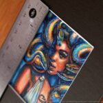 A portrait of Medusa with colorful snakes. Miniature painting. Ruler for scale