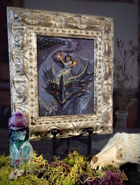 A framed picture of a fire fairy riding a dragon