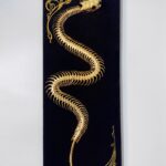 Golden snake skeleton undulates across black velvet