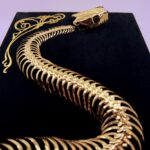 Golden snake skeleton undulates across black velvet