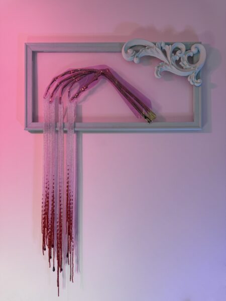 Golden skeletal hand elegantly posed with silver beads dripping from the fingers