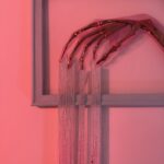 Golden skeletal hand elegantly posed with silver beads dripping from the fingers