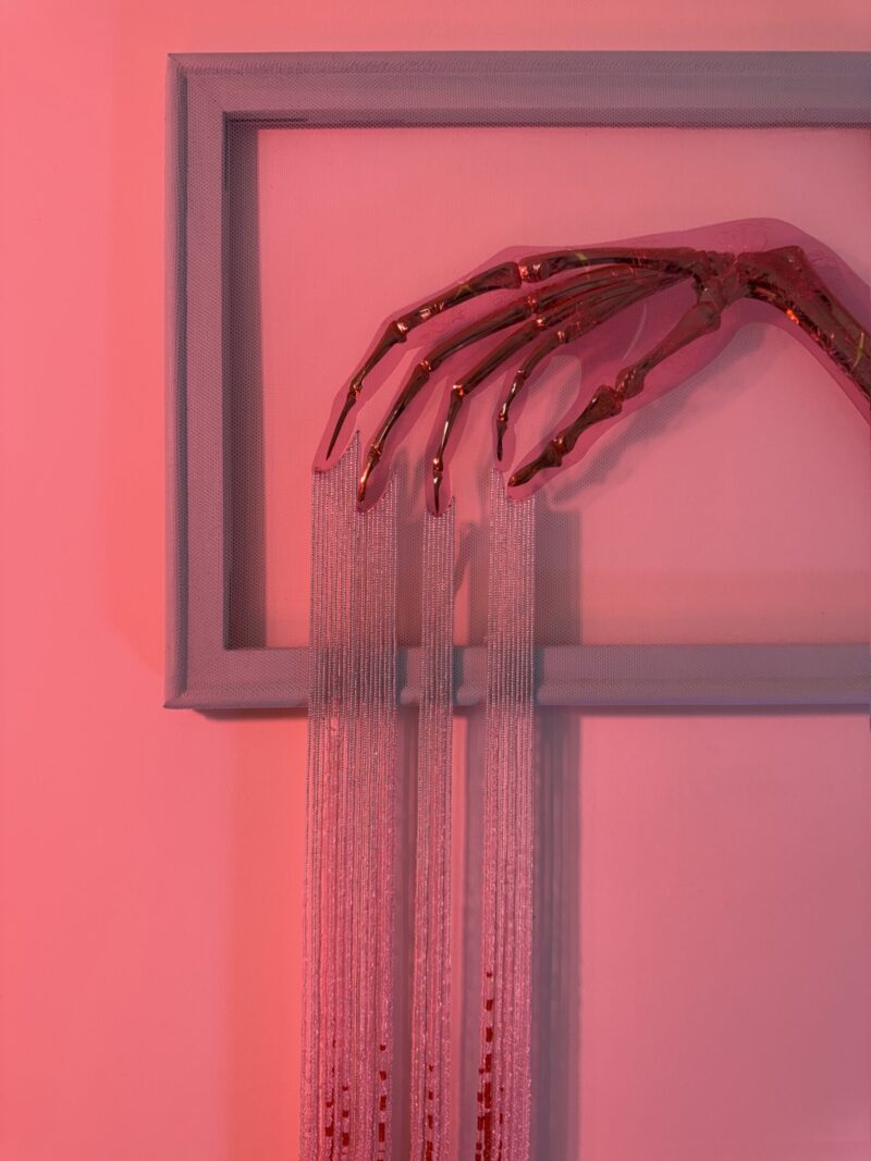 Golden skeletal hand elegantly posed with silver beads dripping from the fingers