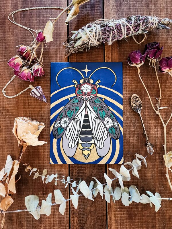 An acryla gouache painting of a lightning bug with gold leaf emanating from its glowing end. The lightning bug is on a blue background and has images of a moonflower plant drawn over its wings and body.