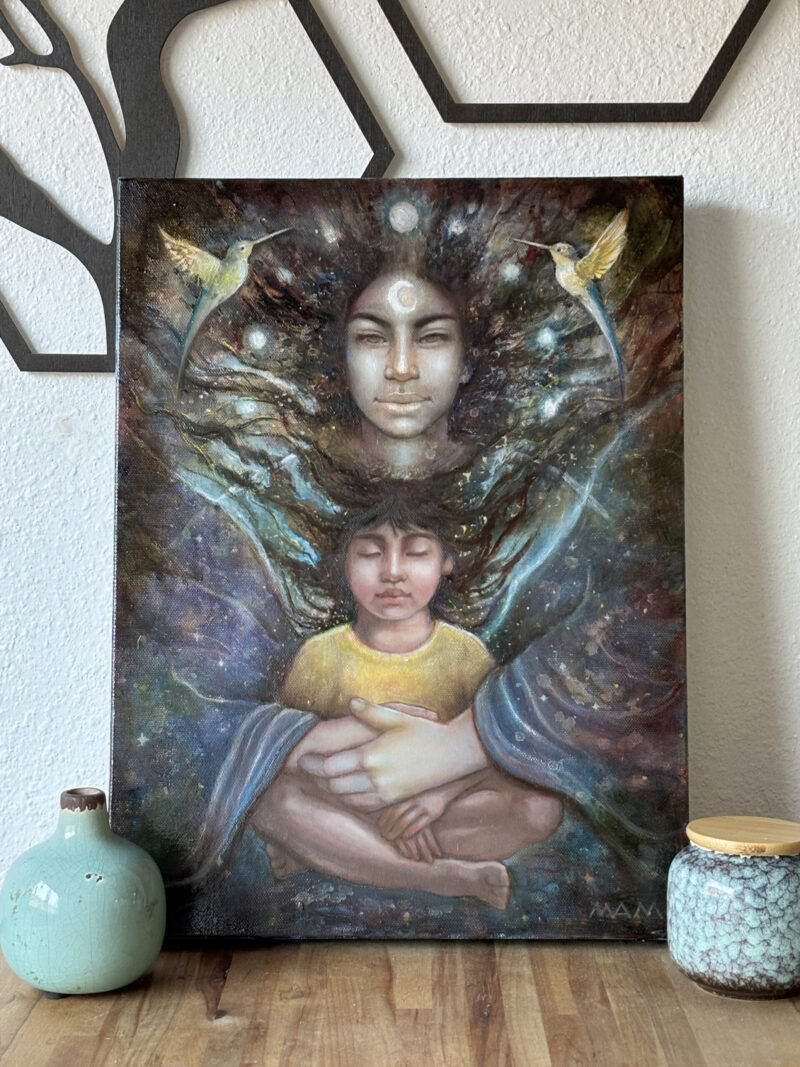 Oil painting Celestial Guardian displayed on a table in natural light, showing a celestial female figure embracing a child with two hummingbirds on either side.