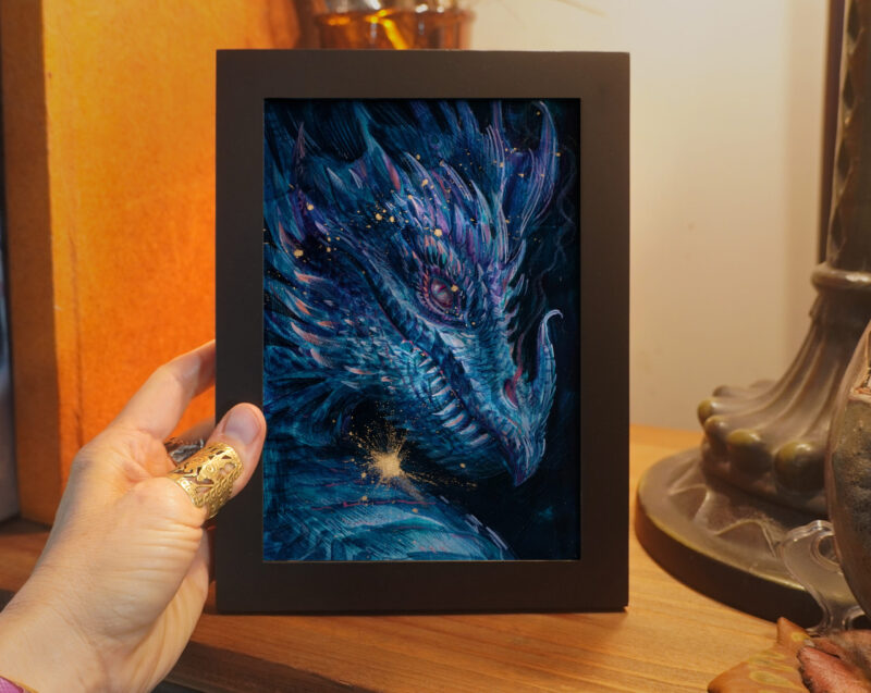 A framed painting illustrating a portrait of a golden cyan dragon