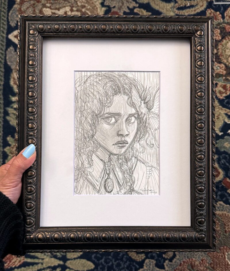 The artist's hand holds the framed 8" x 10" drawing for scale
