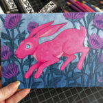 A painting of a pink hare surrounded by purple bee balm bergamot flowers.