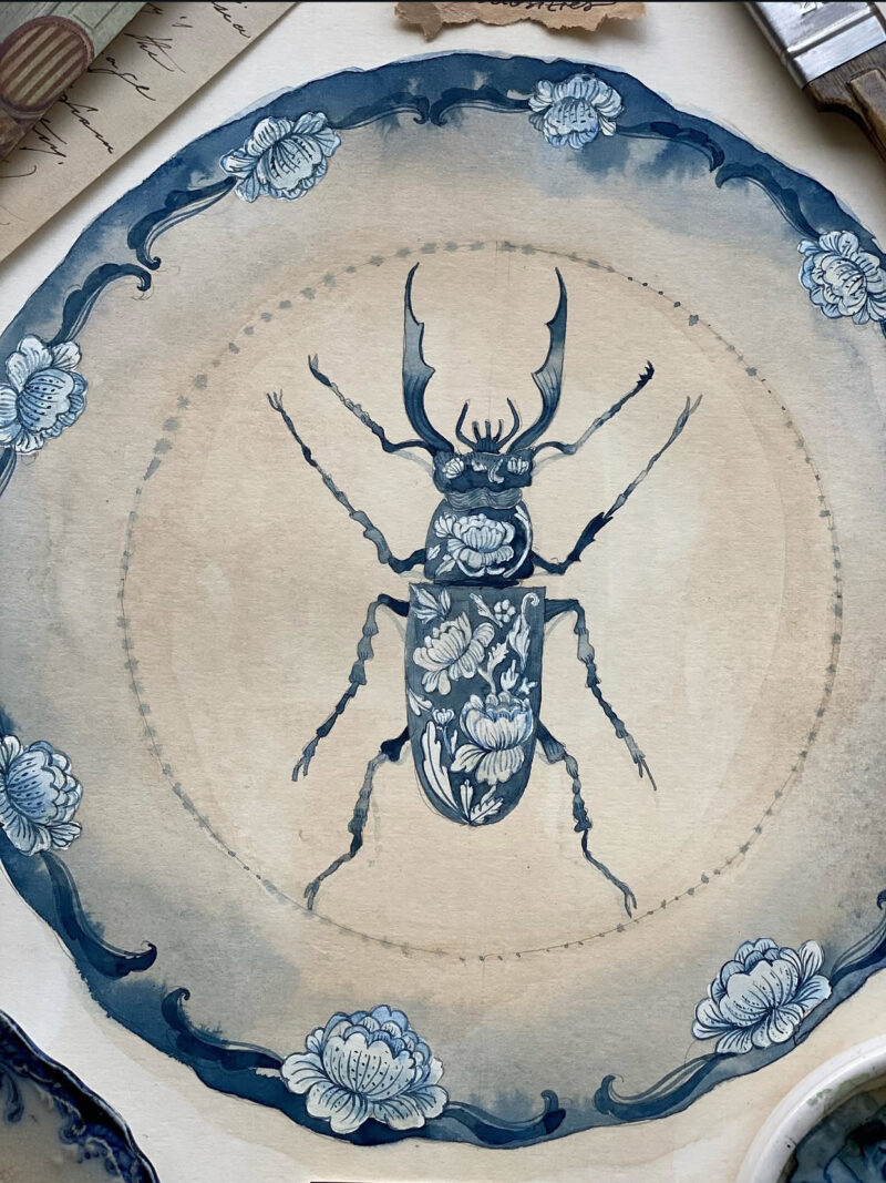 A hand-painted blue-and-white porcelain-style plate featuring intricate floral and vine motifs with a detailed beetle at the center. Inspired by antique Chinese ceramics and natural history collections, the artwork evokes the feeling of a treasured object displayed in a collector's cabinet of curiosities. The plate is photographed against a neutral background.