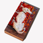 A painting of a Borzoi dog in front of an ornate rug by Sarah Van Rose set at an angle so the viewer can see the side of the wood panel.