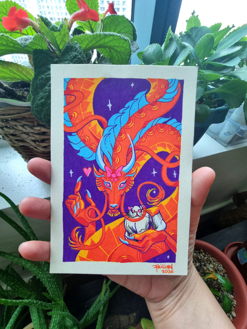 A photo of a colorful, illustrated dragon with a pink bow on its head holding a white fluffy cat. It is held by a right hand with potted plants in the background.