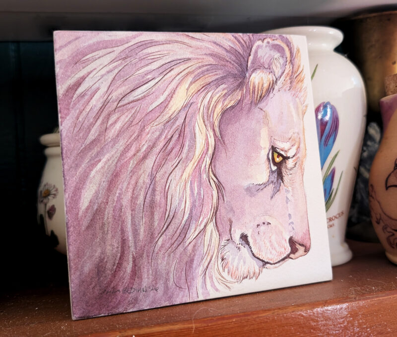 photo of a painting with jars in the background. Square watercolor painting is of a lion head in pale violets, pinks and creams